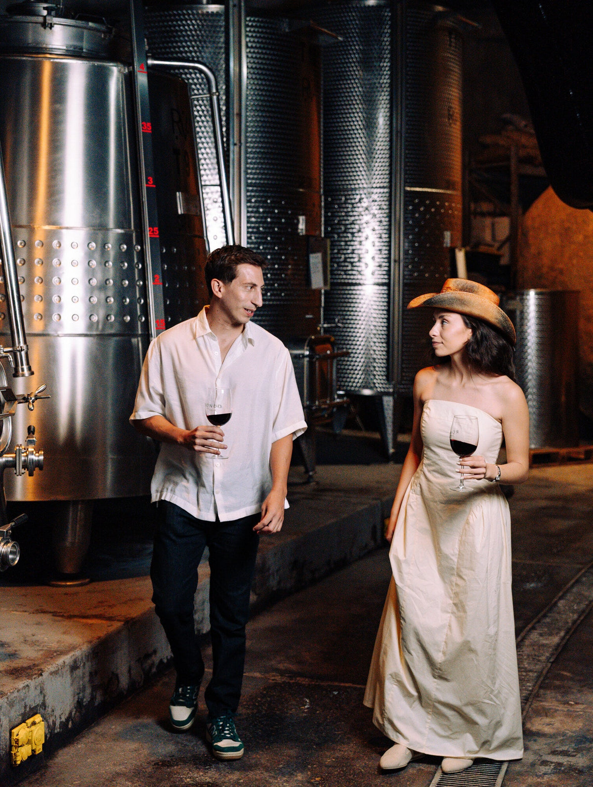 Pareja recorriendo la zona de vinificación de Rondo del Valle con copas de vino