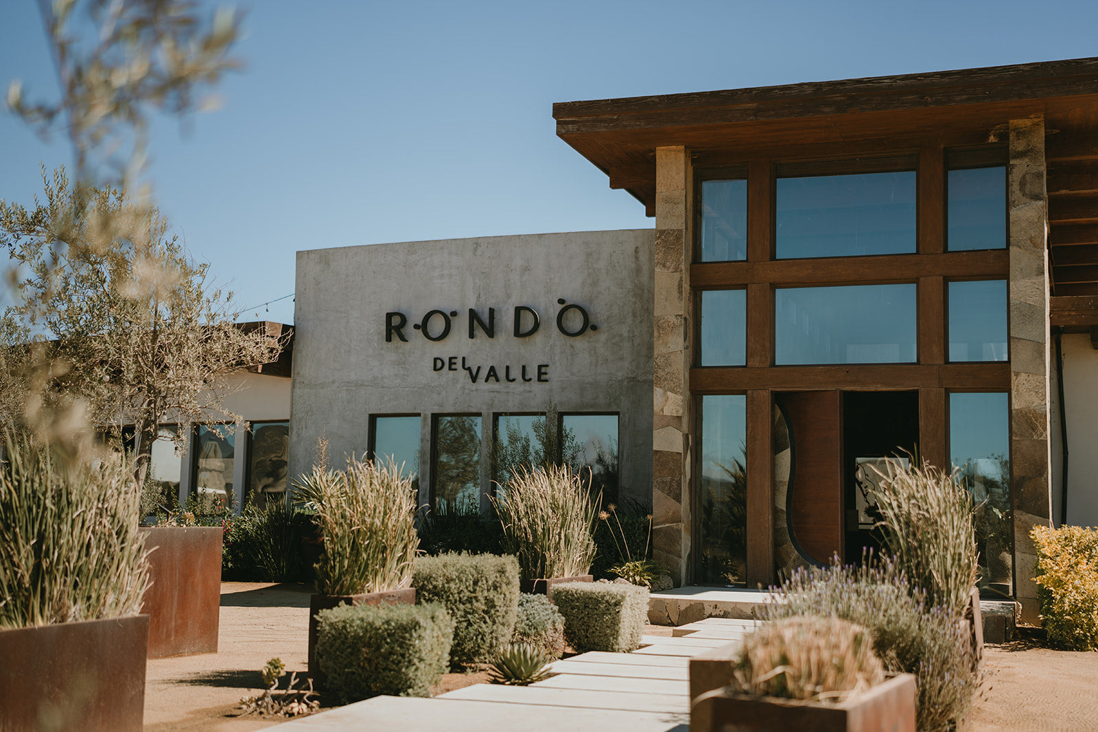 Entrada de la vinícola Rondo del Valle con fachada moderna y jardines, Valle de Guadalupe, México | Entrance of Rondo del Valle winery with modern facade and gardens, Valle de Guadalupe, Mexico